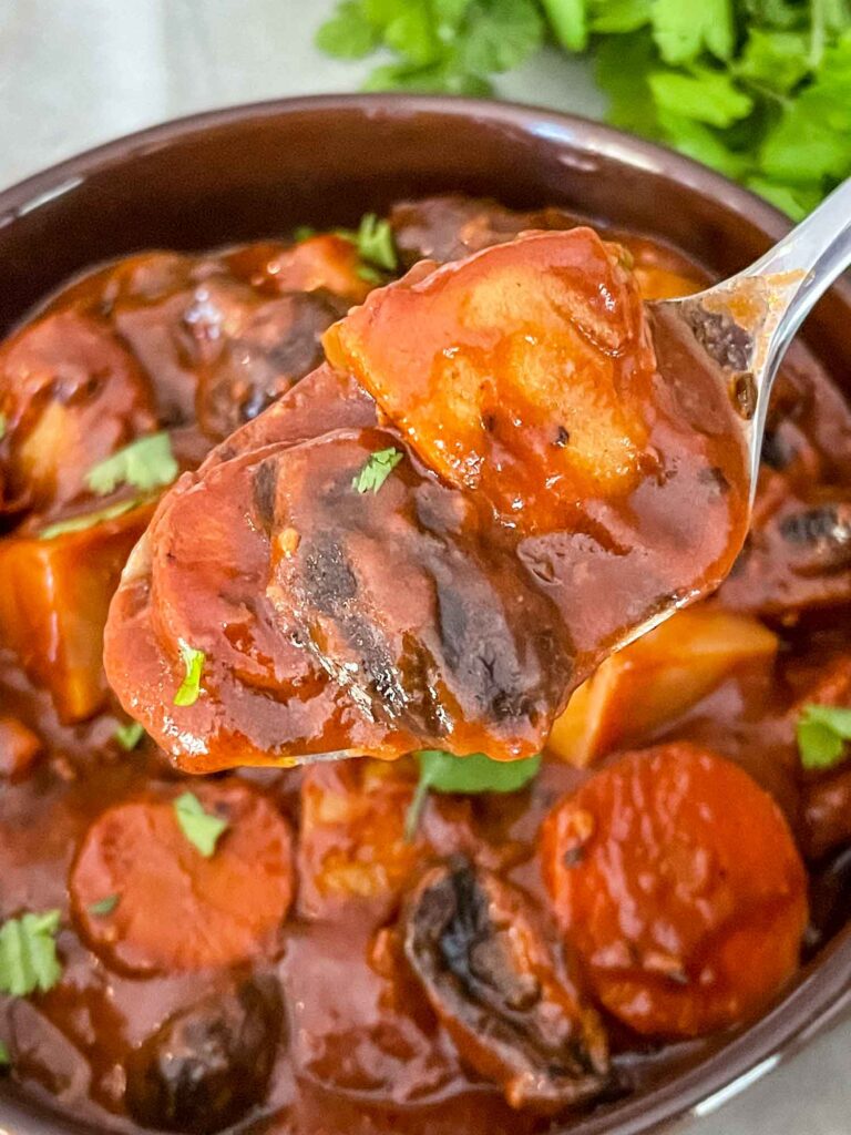 A spoon of Vegan Stew above a bowl