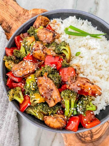 Top view of Teriyaki Chicken Stir Fry in a gray bowl with white rice. Sitting on a wood board on a counter