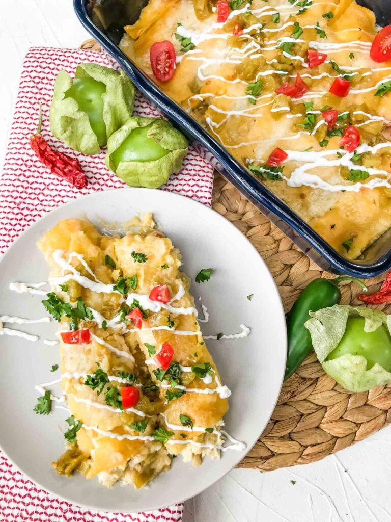 Top view of some Creamy Chicken Enchiladas on a plate with the dish next to it