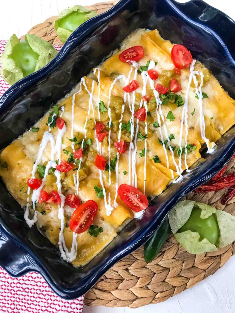 Creamy Chicken Enchiladas after cooking in a blue dish with tomatoes on top