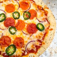 An entire 30 Minute Homemade Pizza topped with peppers, pepperoni, and onion sitting on a baking sheet