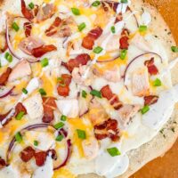 Top view of a Chicken Bacon Ranch Pizza fresh out of the oven on top of a pizza peel