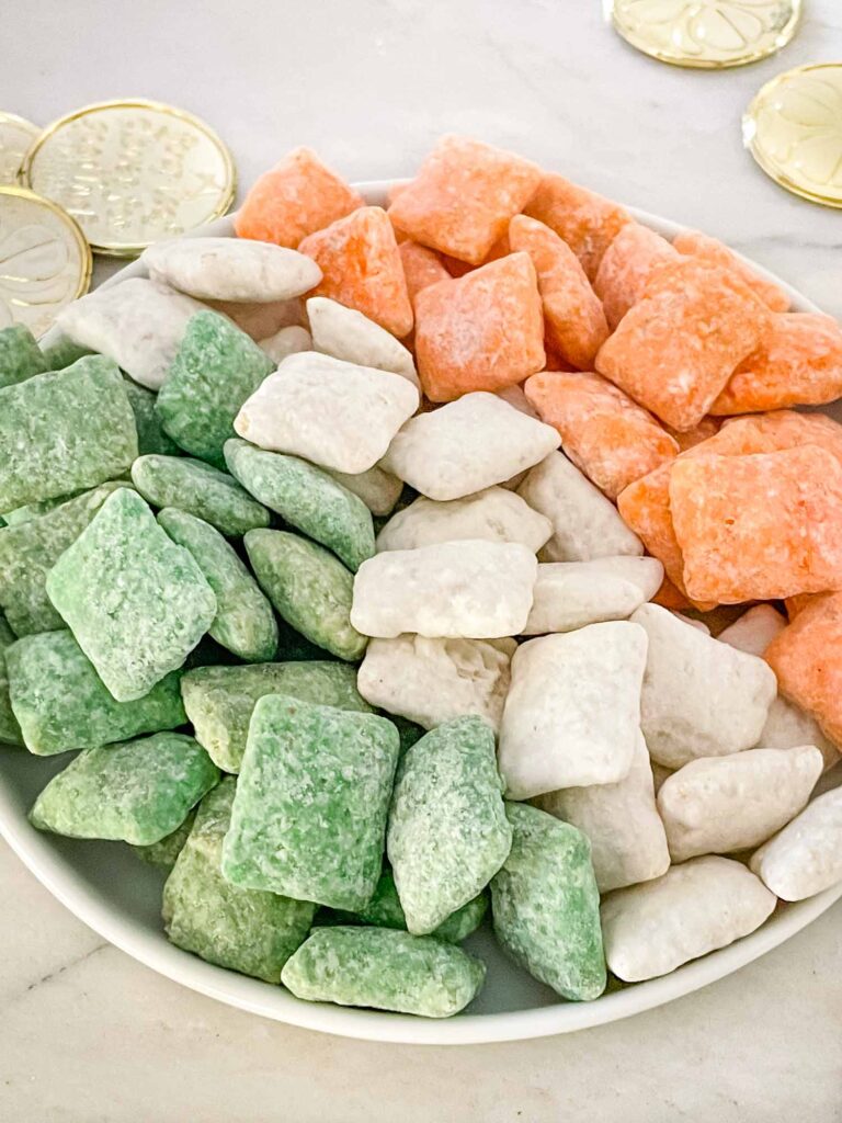 Green, white, and orange Leprechaun Puppy Chow laid out on a plate to look like the Irish flag