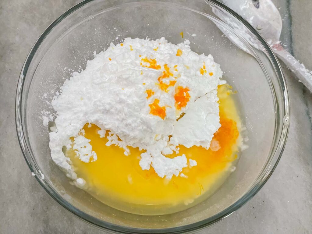 The ingredients for Orange Glaze in a clear bowl before mixing