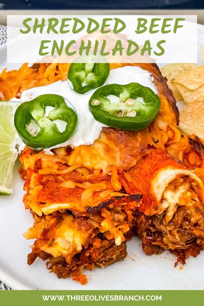 Pin of two Shredded Beef Enchiladas on a white plate with sour cream and jalapenos on them. Title at top.