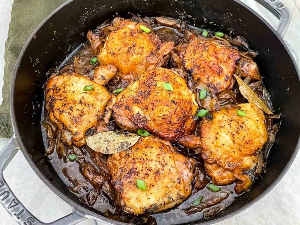 Beer Braised Chicken Thighs in a braiser after cooking sitting on a counter