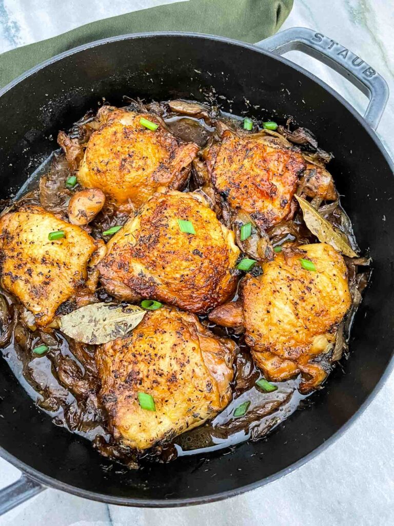 The Beer Braised Chicken Thighs in a braiser from the top view sitting on a counter