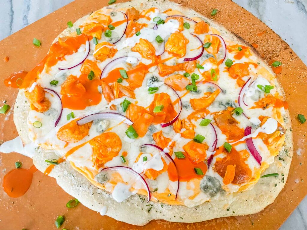 A whole Buffalo Chicken Pizza sitting on a pizza peel
