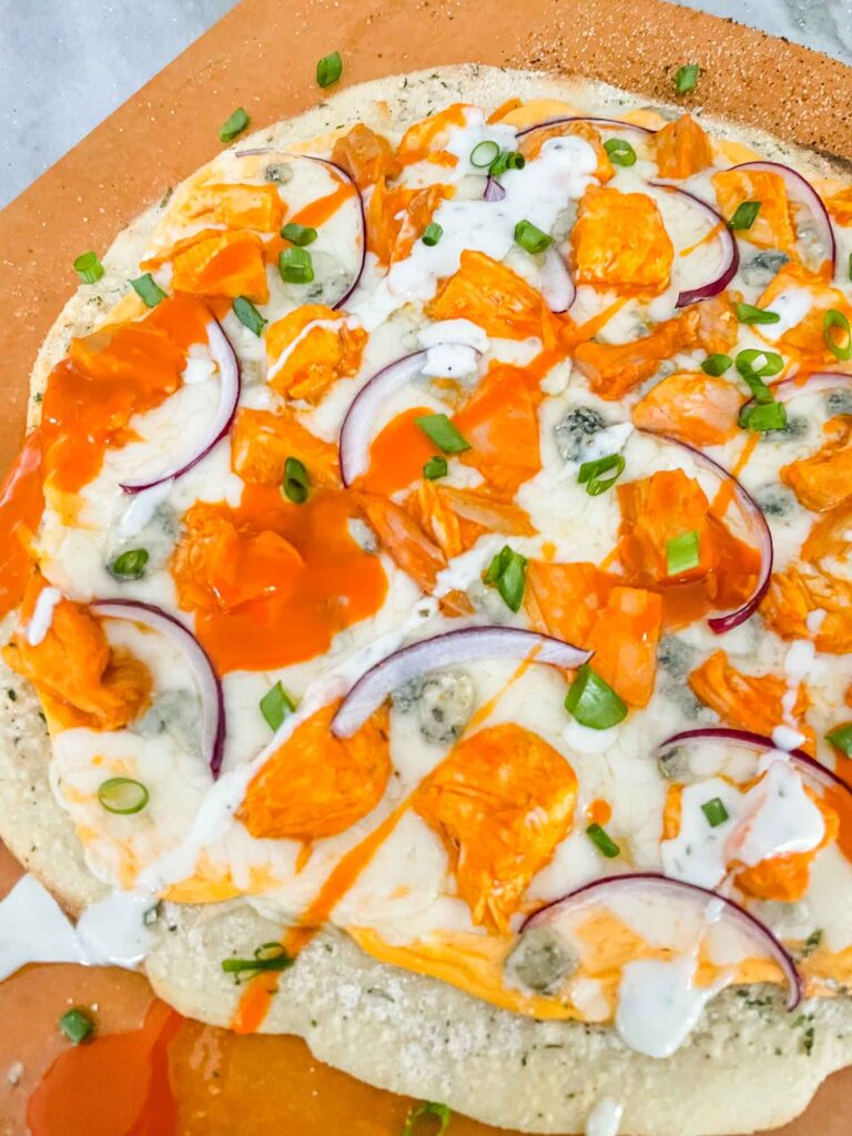 Closer view of a whole Buffalo Chicken Pizza sitting on a pizza peel