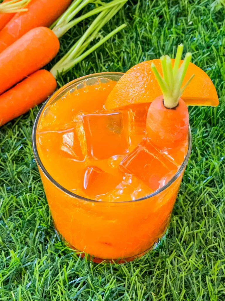 Top view of Carrot Patch Mocktail in a glass sitting on grass