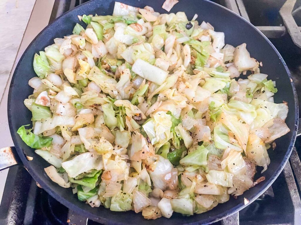The cabbage and onion mixture cooking in a skillet