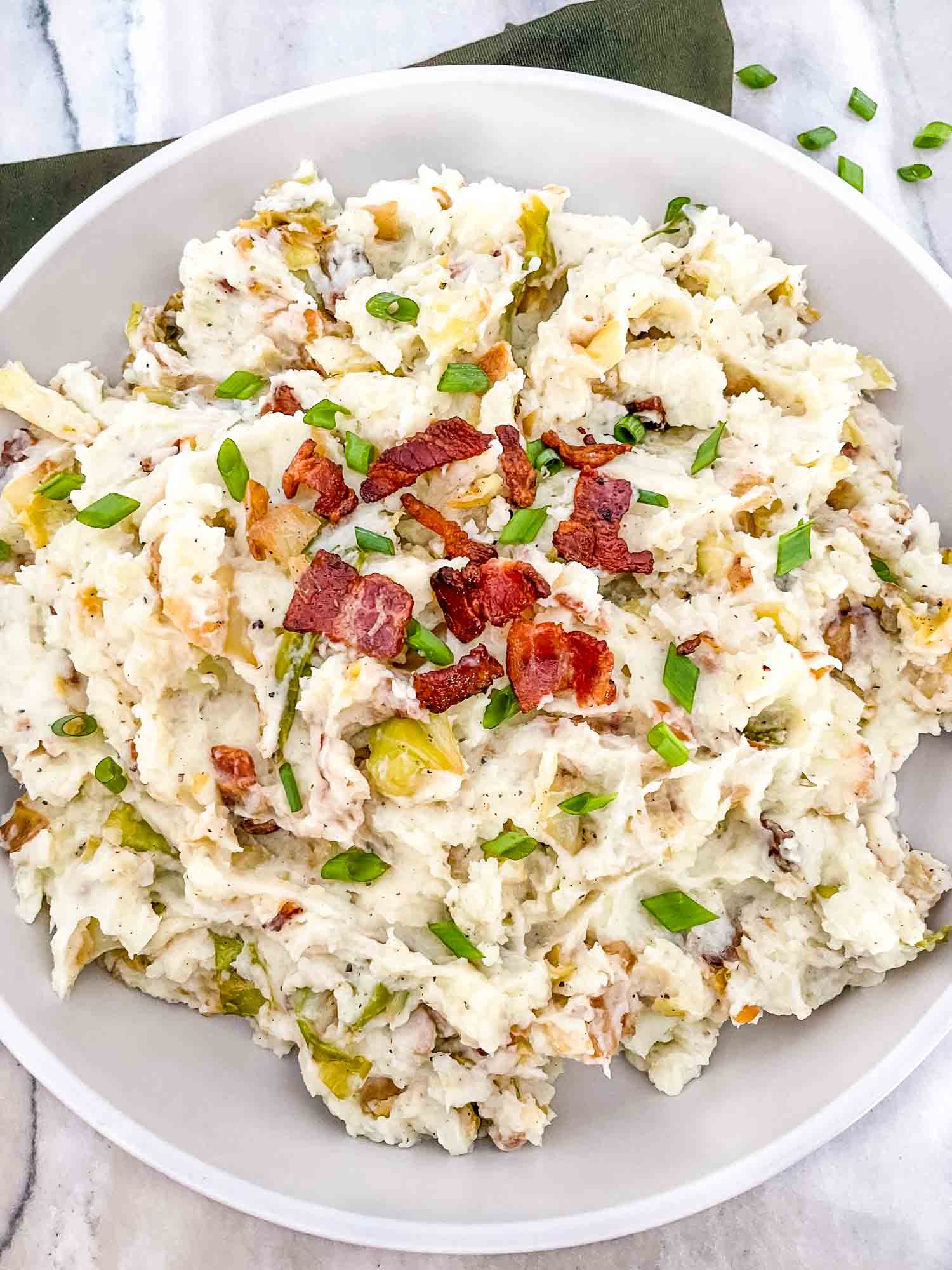Top view of Colcannon with Bacon in a large, shallow white serving dish sitting on a counter