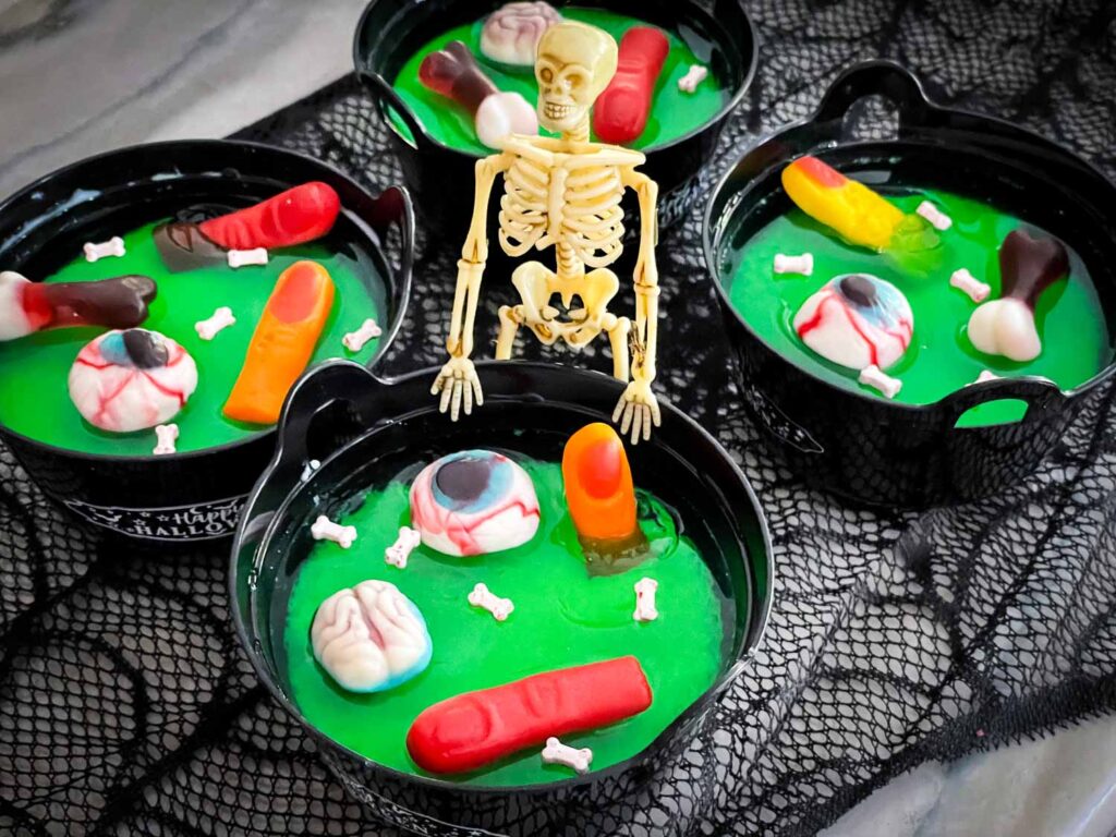 Halloween Jello Cauldrons with a skeleton standing at one