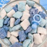 Top view of It's a Boy Puppy Chow in blue and white in a bowl with a plastic pacifier and title at top