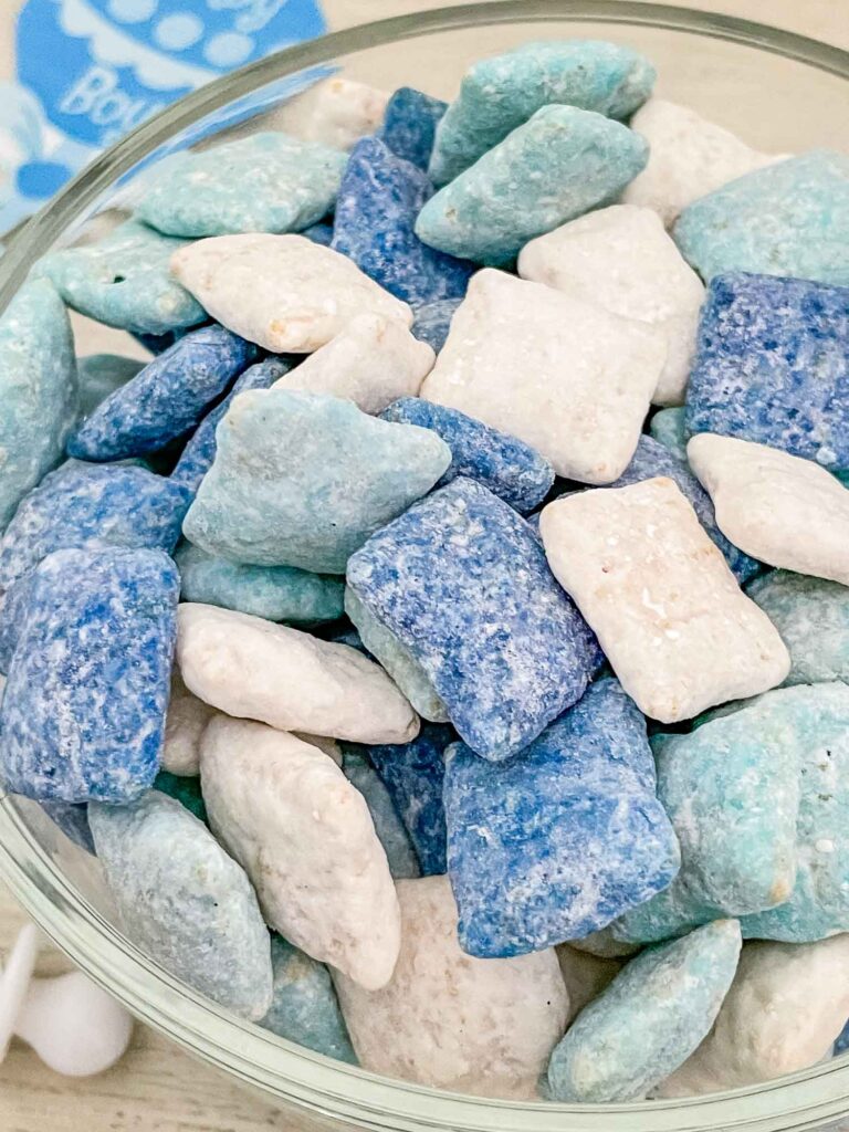 Close view of dark blue, light blue, and white It's a Boy Puppy Chow in a clear bowl