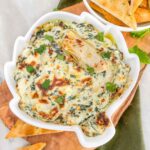 Top view of Easy Spinach Artichoke Dip in an artichoke shaped dish on a wood board