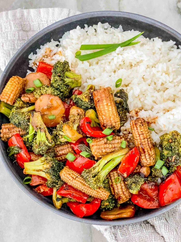 Vegetable Teriyaki Stir Fry piled in a bowl with white rice sitting on a counter