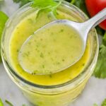 Top view of Cilantro Lime Vinaigrette Salad Dressing in a jar with a spoon full of the dressing coming out of it