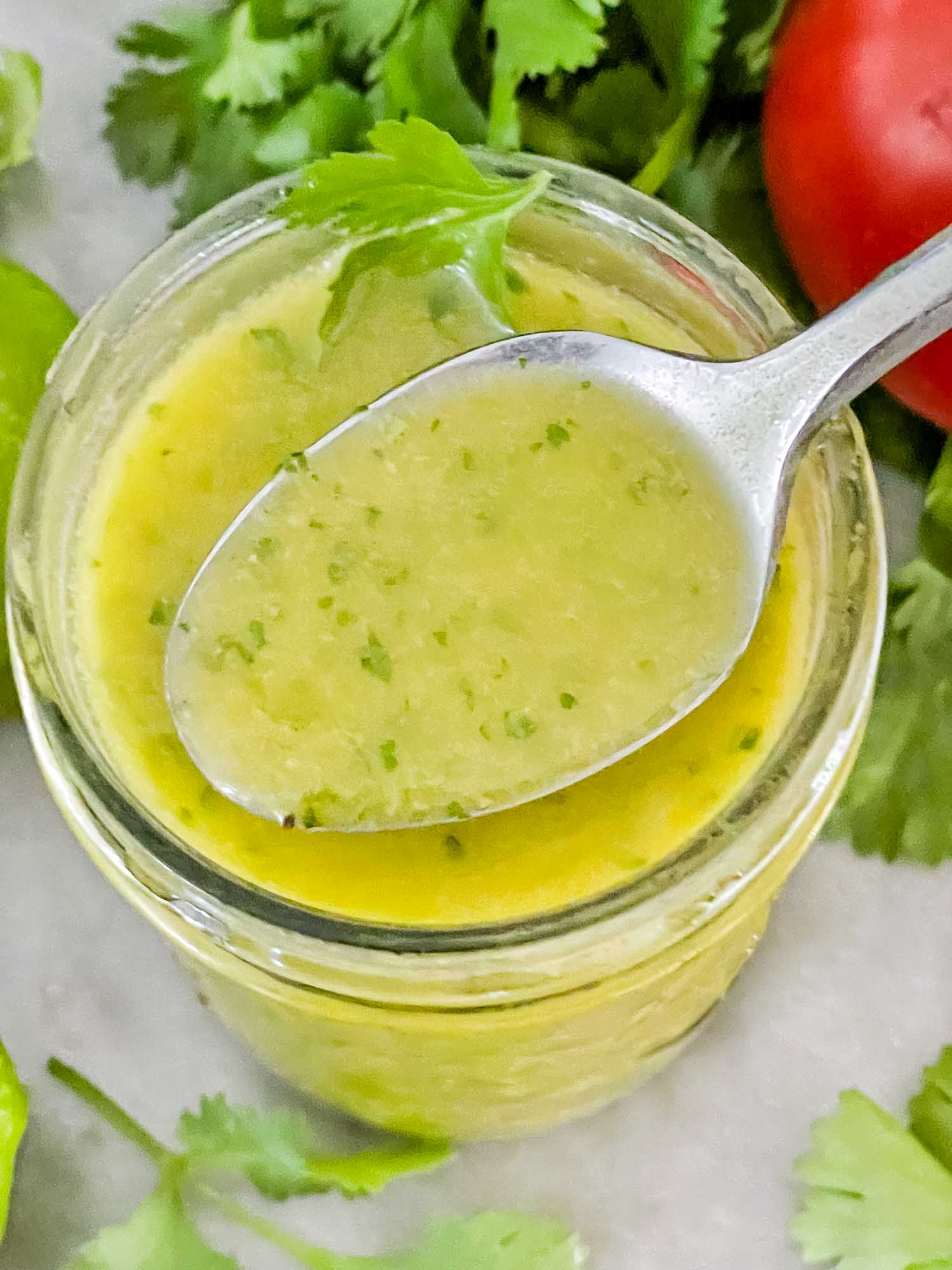 Top view of Cilantro Lime Vinaigrette Salad Dressing in a jar with a spoon full of the dressing coming out of it