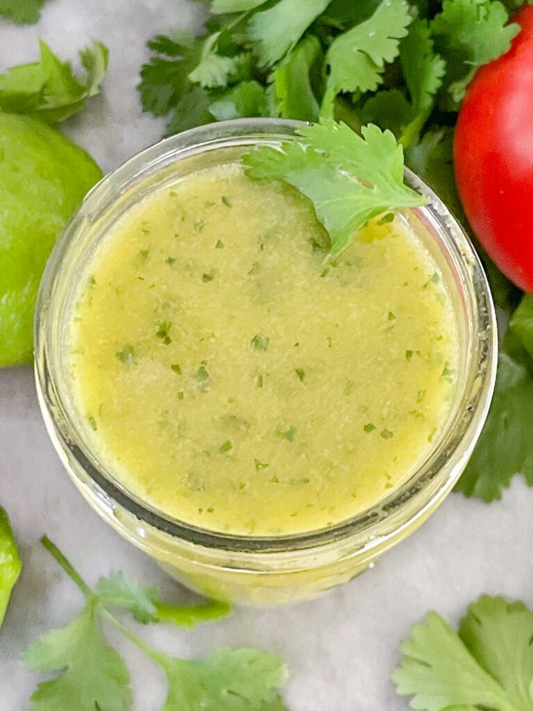 Top view of Cilantro Lime Vinaigrette Salad Dressing in a jar with cilantro around it