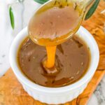 A spoon pouring Honey Mustard Glaze into a small white dish