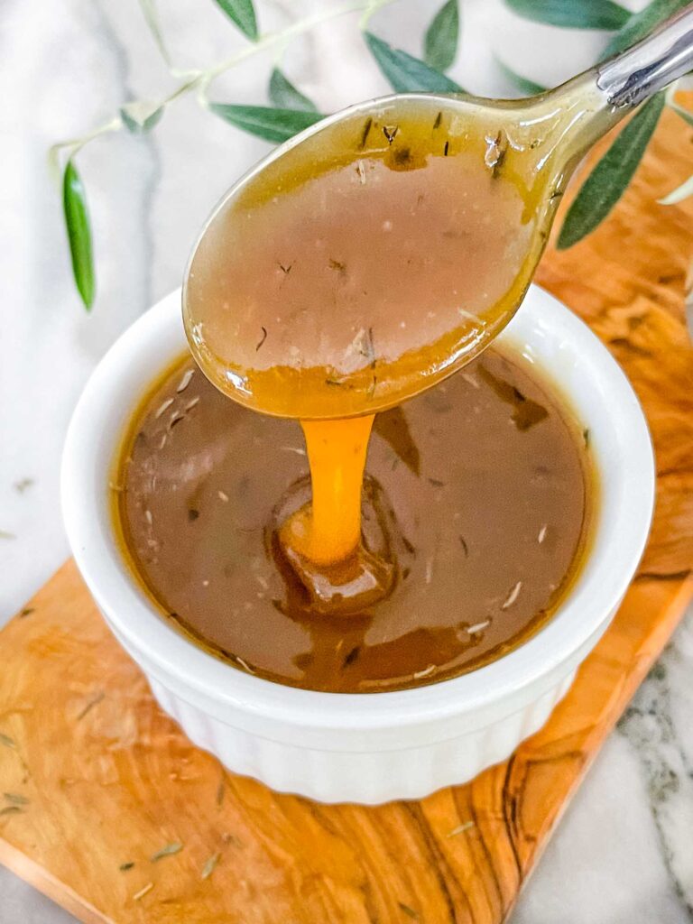 A spoon pouring Honey Mustard Glaze into a small white dish