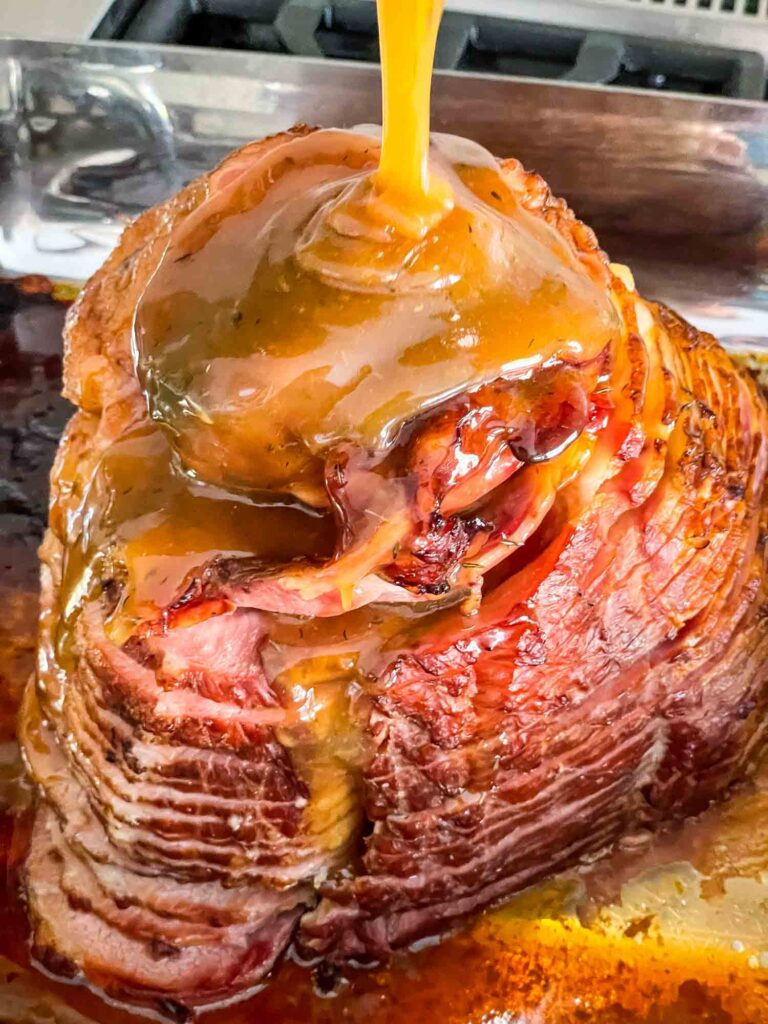The glaze being poured over the ham near the end of cooking