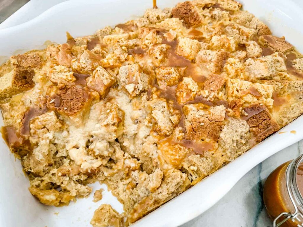 A white dish full of Irish Cream Bread Pudding with a portion missing