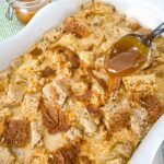 A spoon pouring Bailey's Dessert sauce over a full dish of Irish Cream Bread Pudding