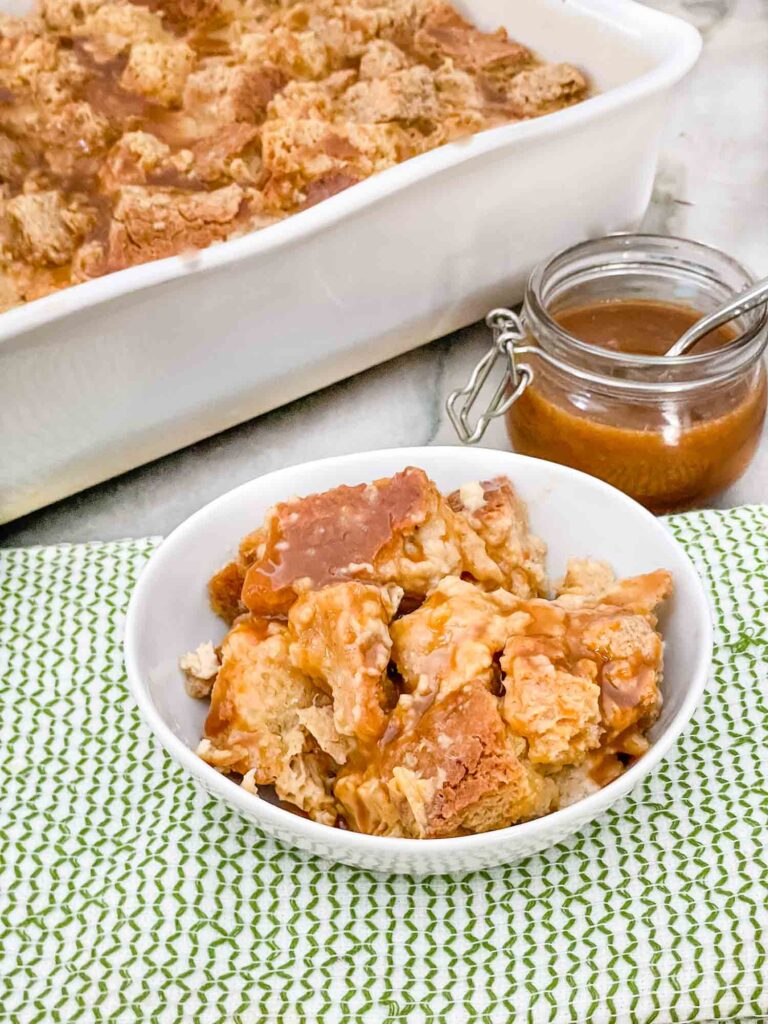 A portion of Bailey's Irish Cream Bread Pudding in a small bowl on a green towel