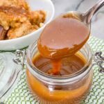 Irish Cream Dessert Sauce in a small clear jar with a spoon having come out of the jar sitting on a green and white towel