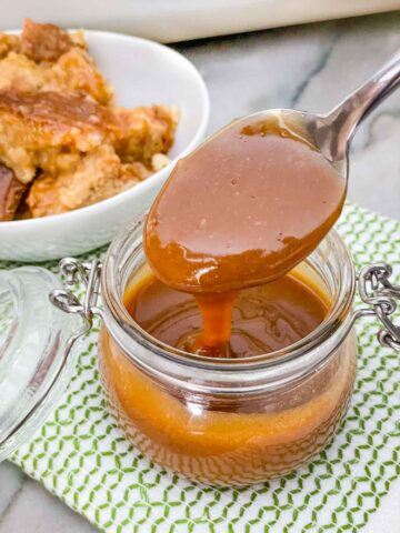 Irish Cream Dessert Sauce in a small clear jar with a spoon having come out of the jar sitting on a green and white towel