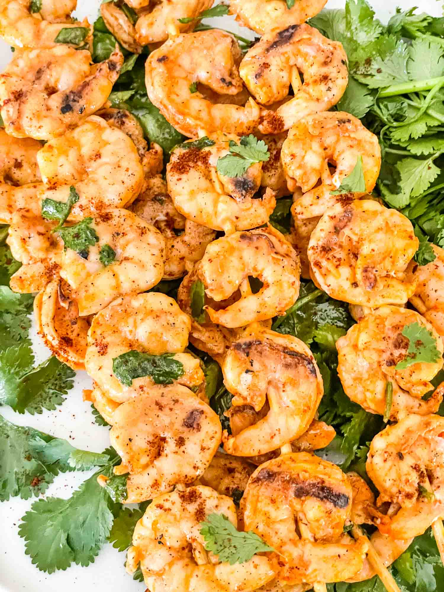 Mexican Grilled Shrimp on skewers sitting on cilantro