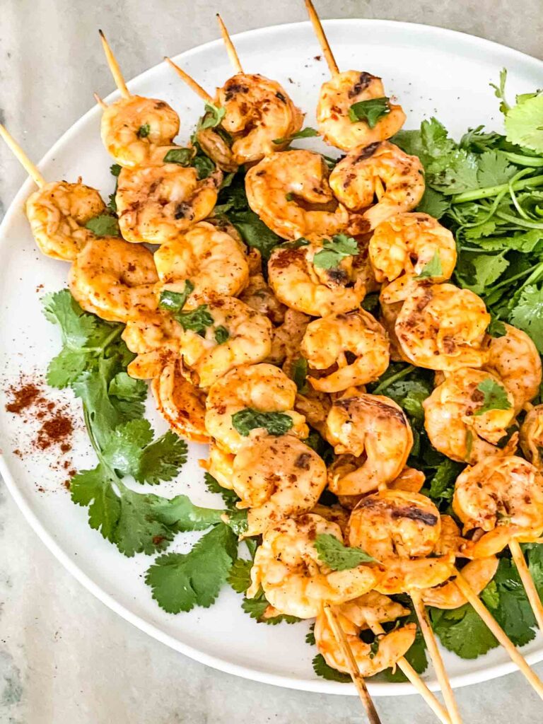 Mexican Grilled Shrimp skewers on cilantro on a white plate