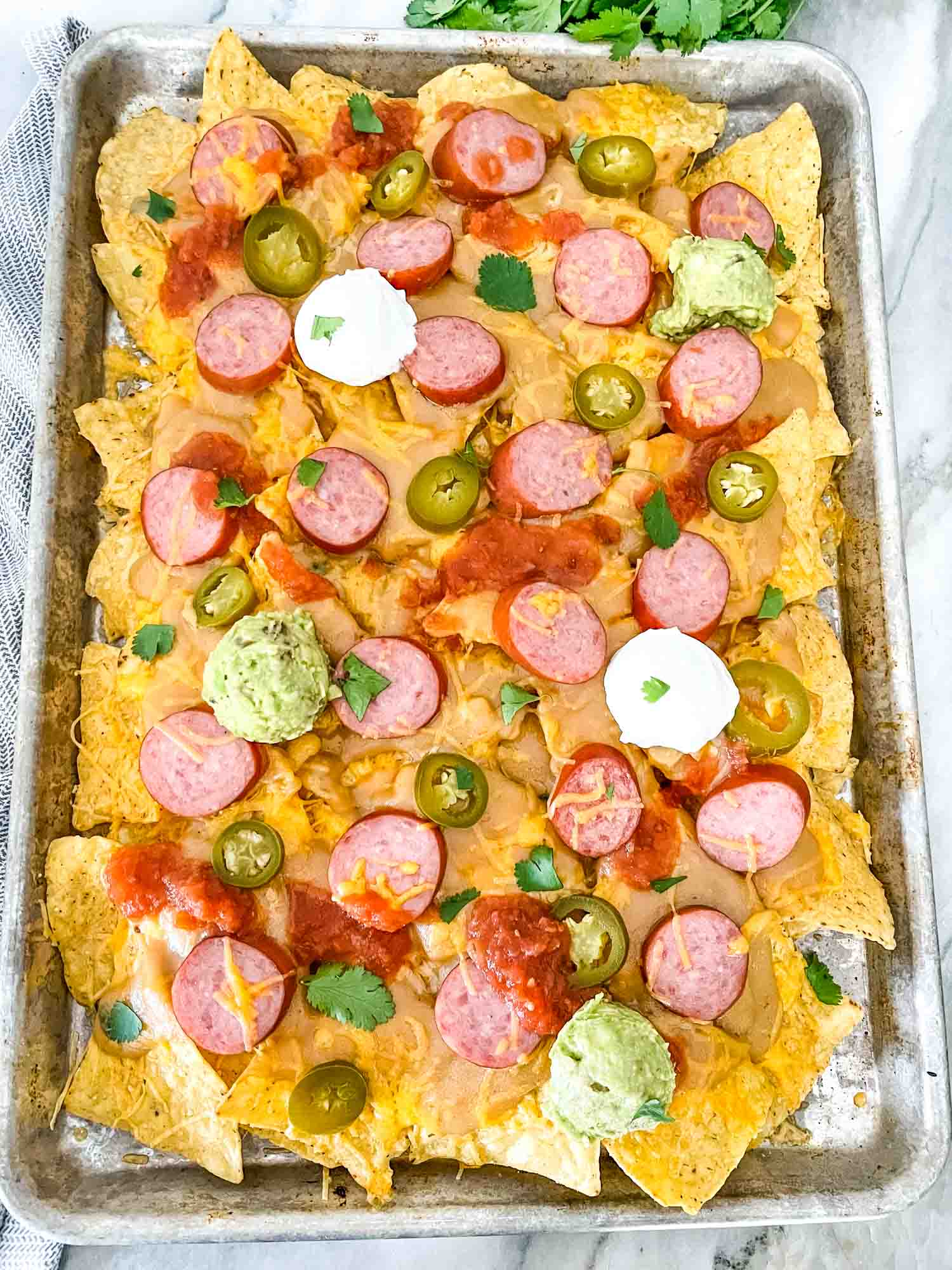 A full baking sheet full of Sausage Beer Cheese Nachos