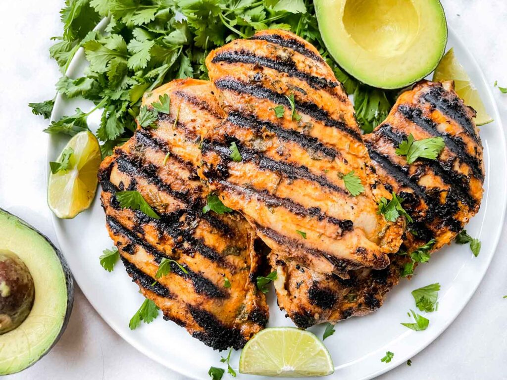 Cilantro Lime Grilled Chicken on a white plate with cilantro and avocado around it
