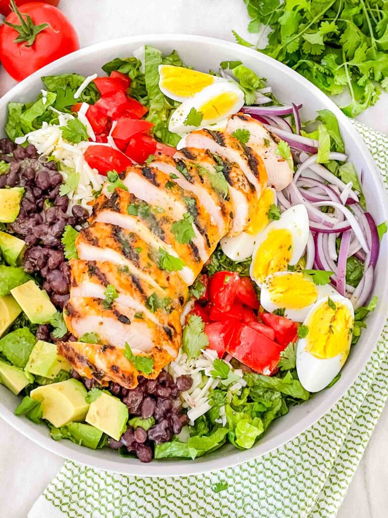 Top view of Mexican Cobb Salad in a shallow bowl with grilled chicken on top sitting on a counter