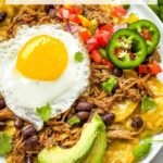 Pin of Pork Carnitas Green Chilaquiles with Eggs on a white plate with title at top.