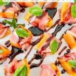 Pin of Prosciutto Wrapped Melon with Balsamic Glaze pieces on a white plate with title at top