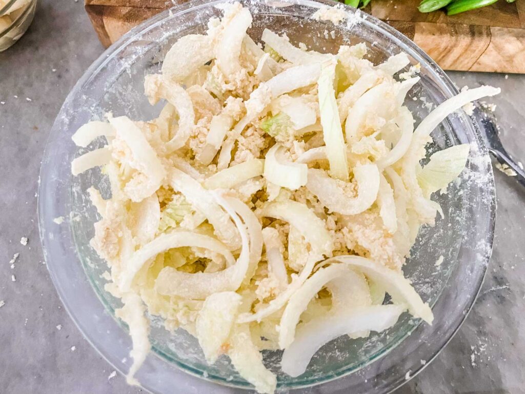 The onions in a bowl after being dredged