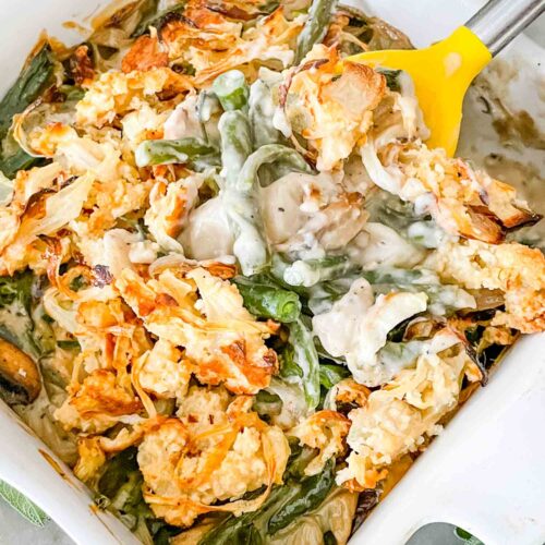 A spoon scooping some Green Bean Casserole with Fresh Green Beans out of a white dish