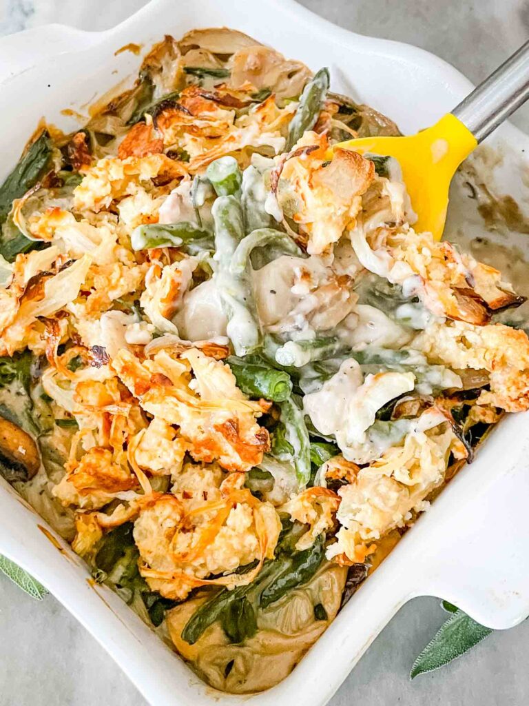 A spoon scooping some Green Bean Casserole with Fresh Green Beans out of a white dish