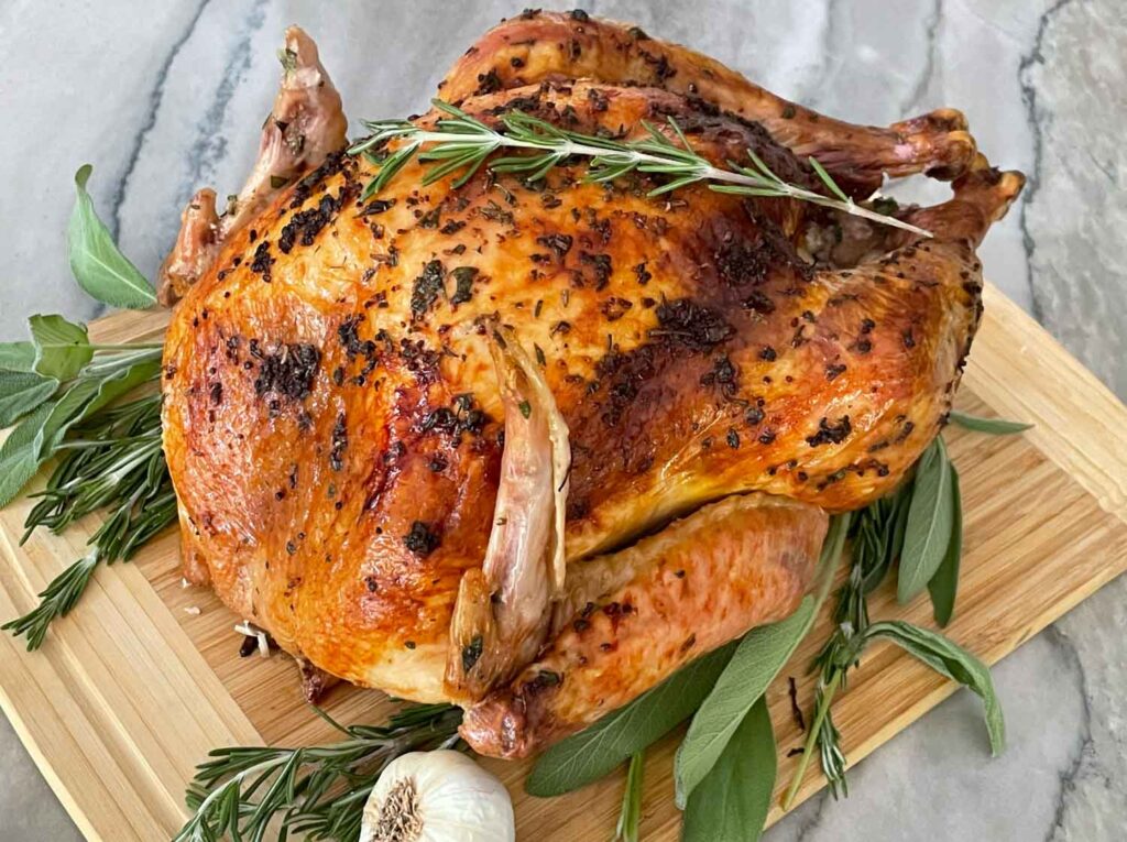 A whole Italian Herb Butter Roasted Turkey on a cutting board on a counter