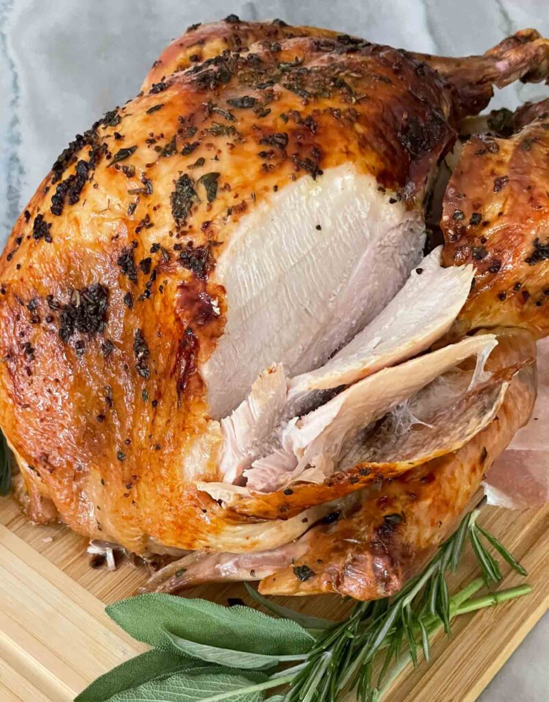 A Italian Herb Butter Roasted Turkey being carved on a cutting board