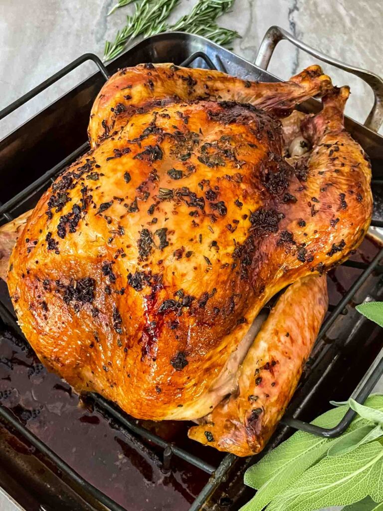 A whole Italian Herb Butter Roasted Turkey in a roasting pan after cooking