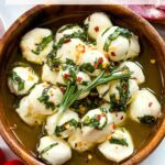 Pin of Marinated Mozzarella Balls from the top view in a wood bowl with title at top