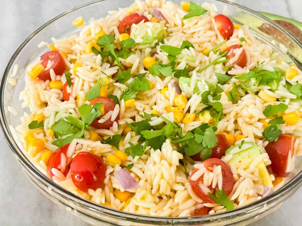 A clear glass bowl with the Mexican Orzo Pasta Salad on a counter