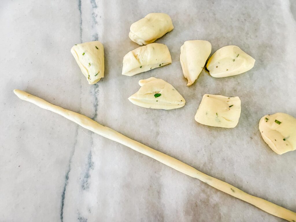 Dough pieces on a counter with one rolled out into a thin stick