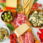 Closer top view of a Antipasti Italian Charcuterie Board on a white counter. Full of meat, cheese, olives, and more.