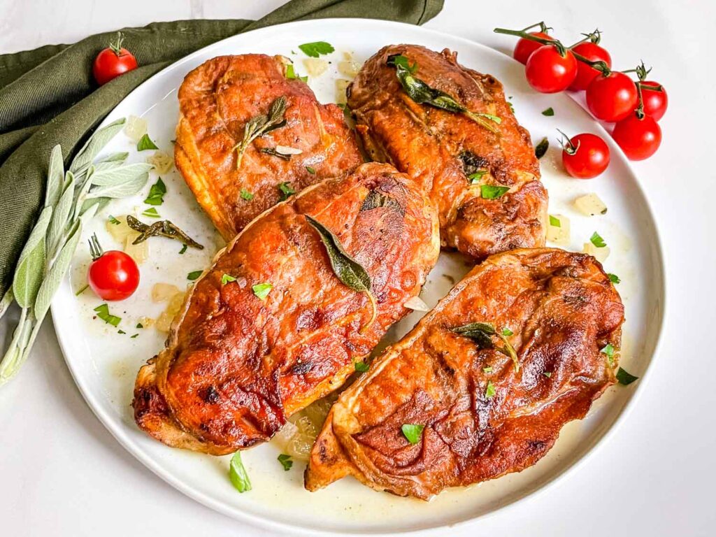 A white plate full of Chicken Saltimbocca alla Romana on a counter.